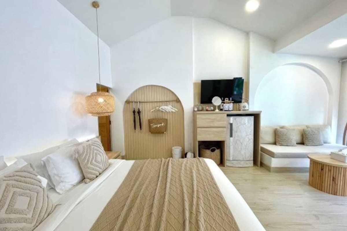 A modern bedroom with a large bed, a TV, a seating area, and a small table.
