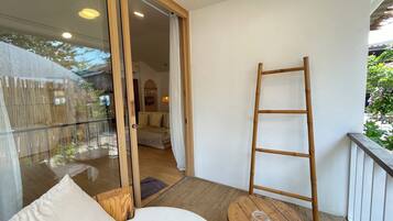 A balcony with a wooden ladder, a round wooden table, and a sofa with cushions.