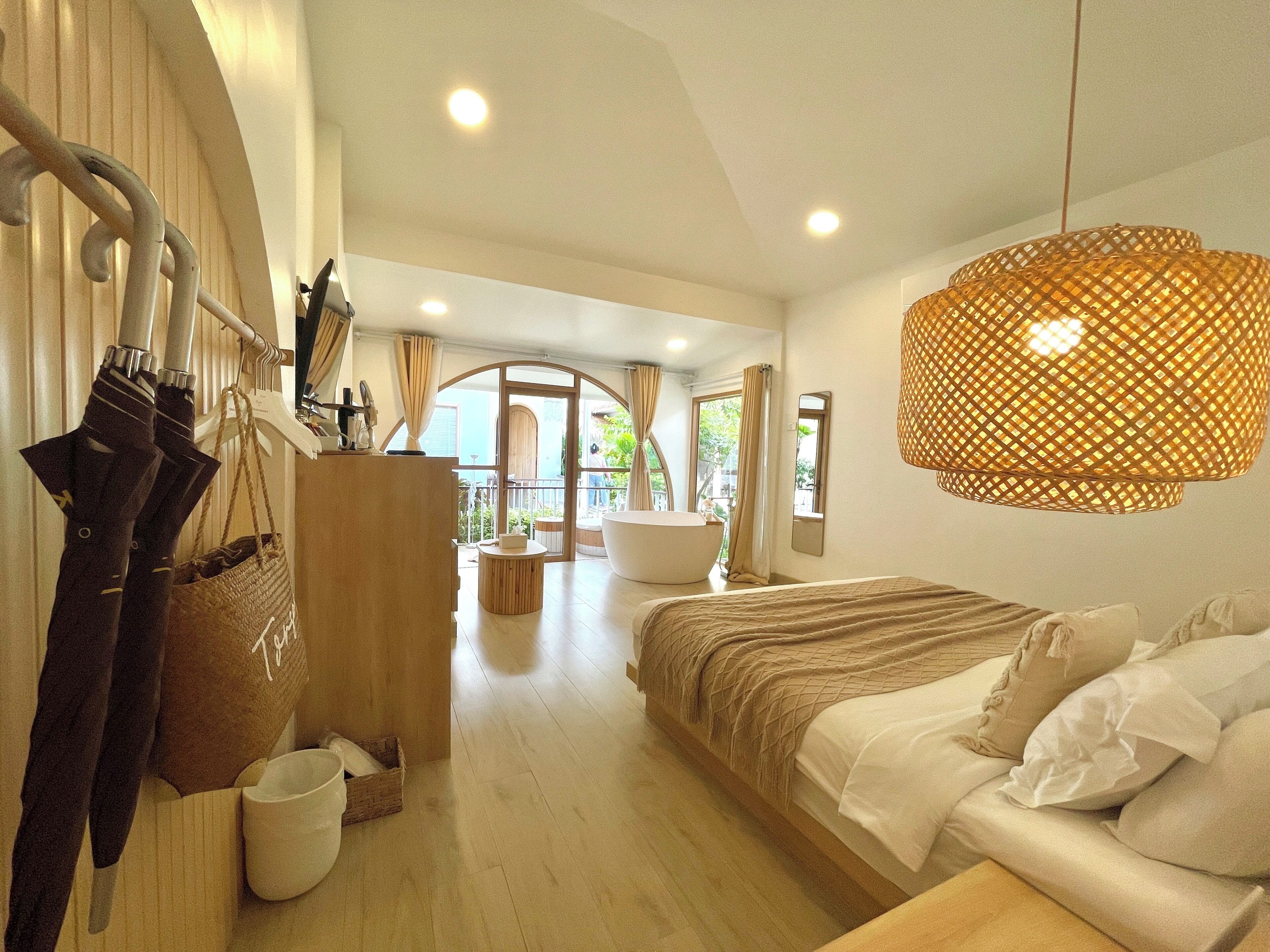 A bedroom with a large bed, a wooden wardrobe, a hanging basket, and a large window.