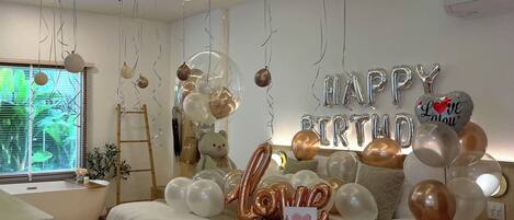 Un dormitorio con cama, ventana y globos.