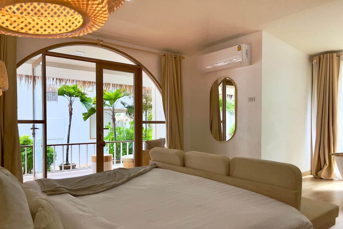 Quarto de hotel com cama grande, varanda com plantas e ar condicionado.