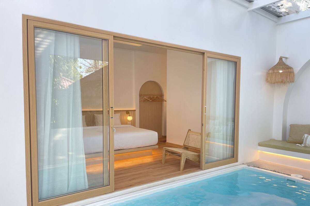 Quarto com porta de vidro que se abre para uma área de piscina.