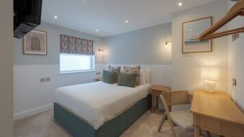A bedroom with a bed, bedside table, lamp, and a window with a floral curtain.