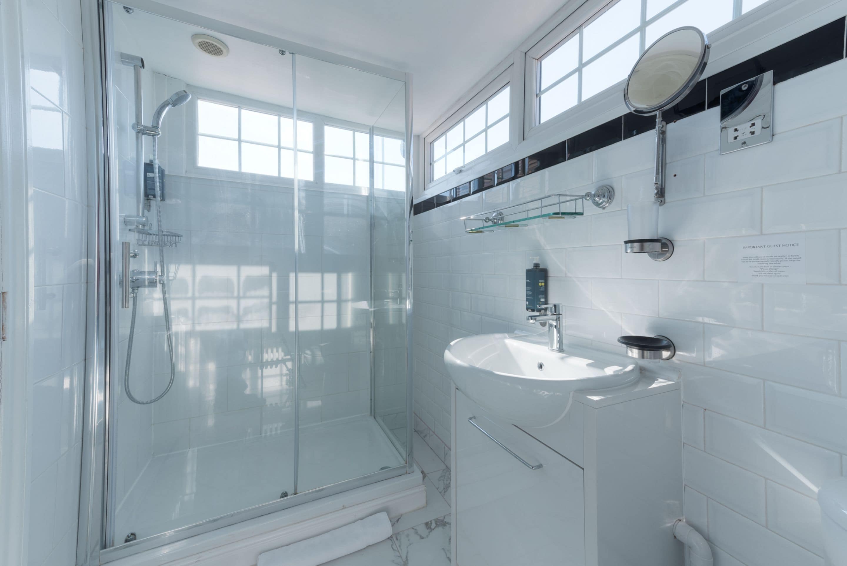 A modern bathroom with a glass-enclosed shower, a white sink, and a mirror above it.