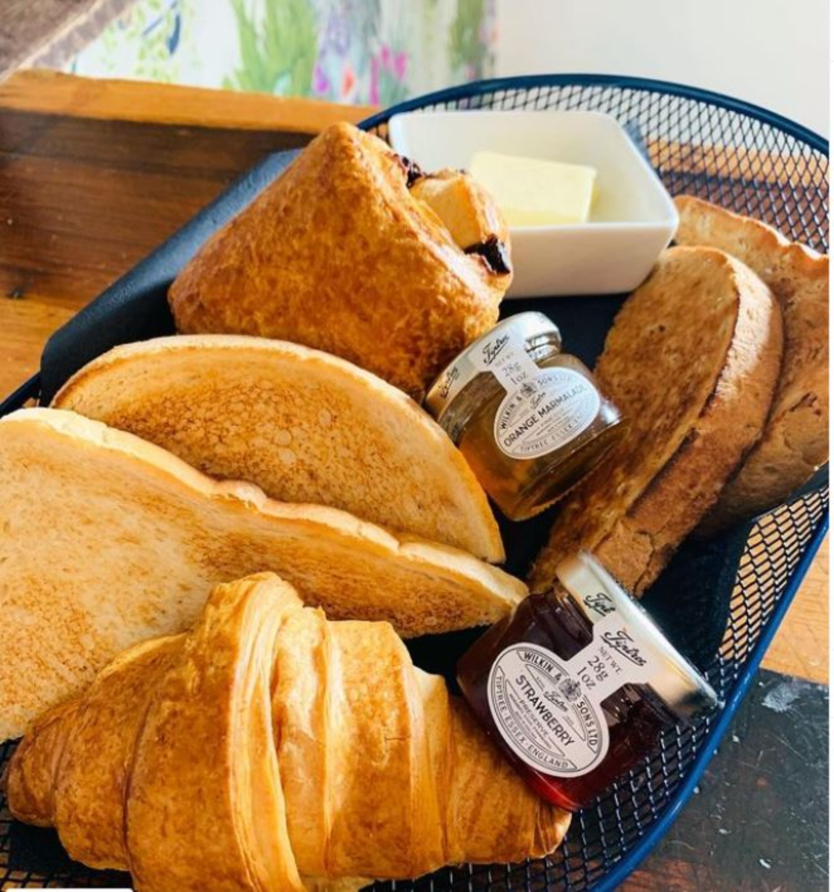 A tray with various types of bread and two bottles of jam.
