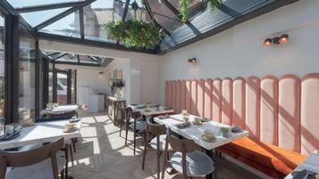 Een restaurant met een glazen dak, houten tafels en stoelen.