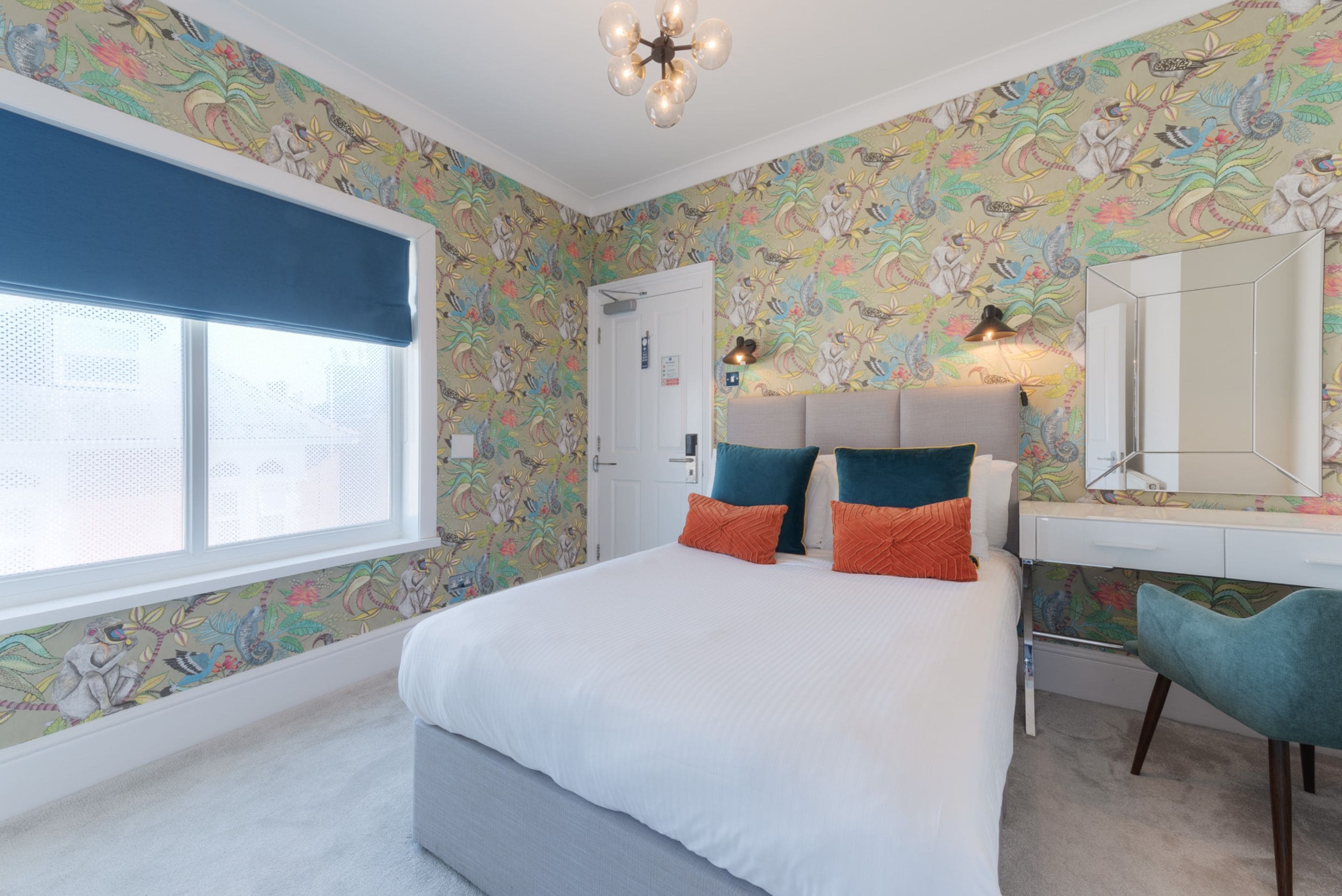 Un dormitorio con cama, cómoda, espejo y ventana con persiana azul.