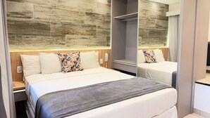 Una habitación de hotel moderna con una cama grande, una mesita de noche, un espejo y un armario.