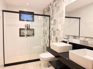 A modern bathroom with a glass-enclosed shower, two sinks, and a toilet. - Pousada Casacolina (Búzios)