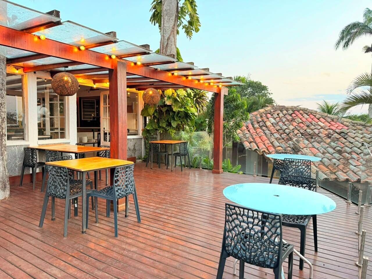 Un patio al aire libre con suelo de madera, mesas y sillas.