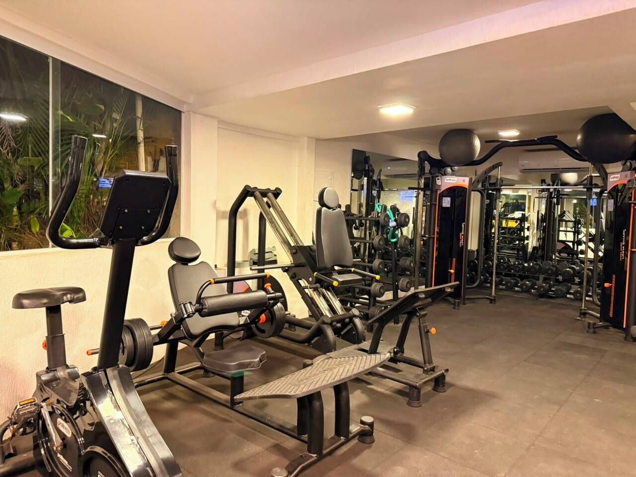 A gym with various exercise equipment, including treadmills, weight machines, and free weights.