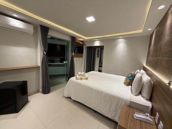A modern hotel room with a bed, bedside table, and a small desk with a phone. - Pousada Casacolina (Búzios)