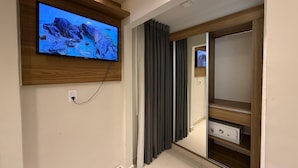 Una habitación moderna con televisión montada, un mueble de madera y una puerta corredera.
