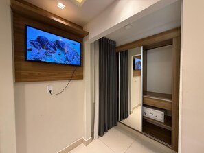 A modern room with a mounted TV, a wooden cabinet, and a sliding door. - Pousada Casacolina (Búzios)