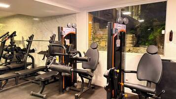 A gym with various exercise machines, a stone wall, and a large window.