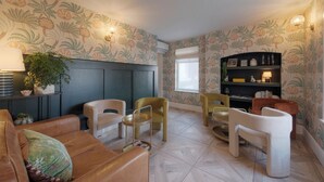 Una habitació amb un armari de fusta fosca, una taula rodona amb cadires, un sofà i una prestatgeria.