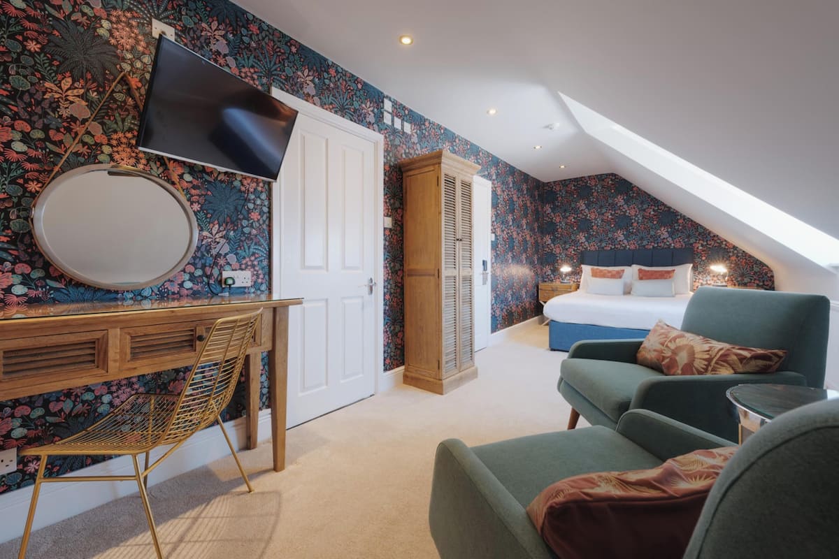 A bedroom with a bed, a desk with a chair, a TV, and a wardrobe.