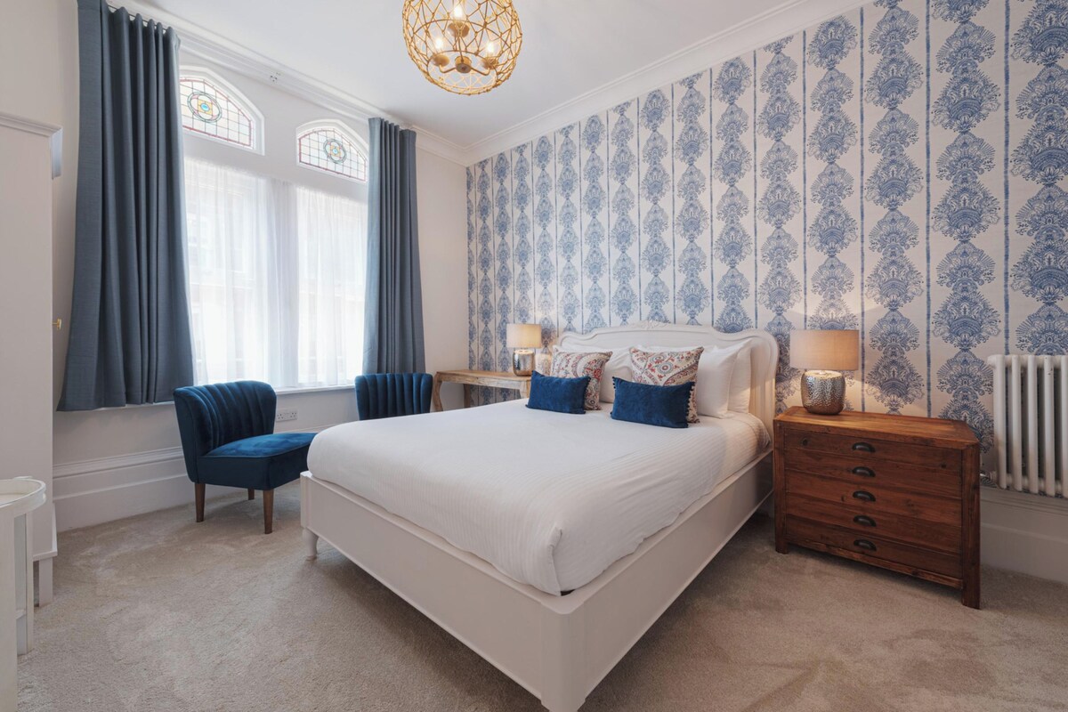 A bedroom with a large bed, a chair, a dresser, and a nightstand.