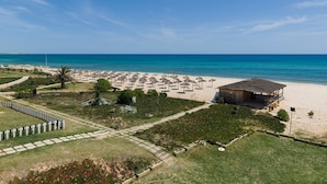 Um imóvel à beira-mar com um amplo terraço, várias guarda-sóis e um pequeno edifício.