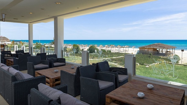 Terraço com móveis de vime e vista para a praia e o oceano.