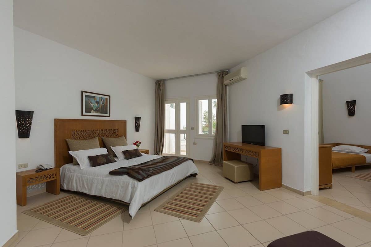 Un dormitorio moderno con una cama grande, un escritorio, una televisión y una pequeña zona de estar.