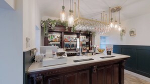 A bar area with a wooden counter, bar stools, a cash register, and a wine cooler. - Florence Gardens Hotel & Restaurant (Portsmouth)