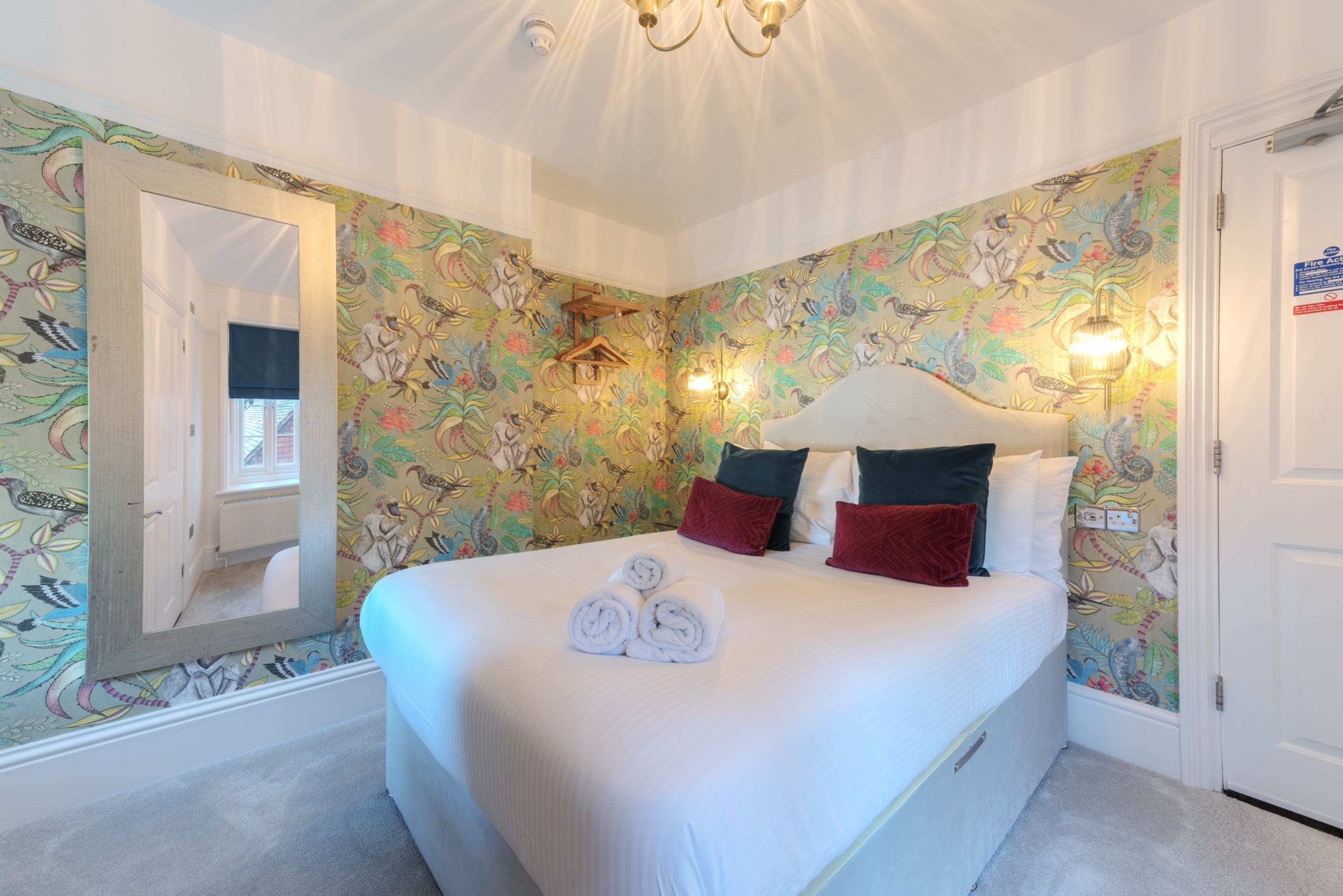 Un dormitorio con una cama grande, papel tapiz floral y un espejo.