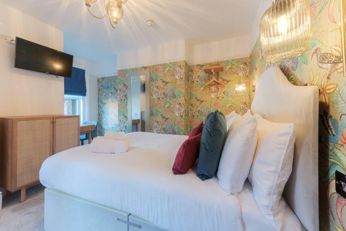 A bedroom with a bed, a TV, a wardrobe, and a mirror.