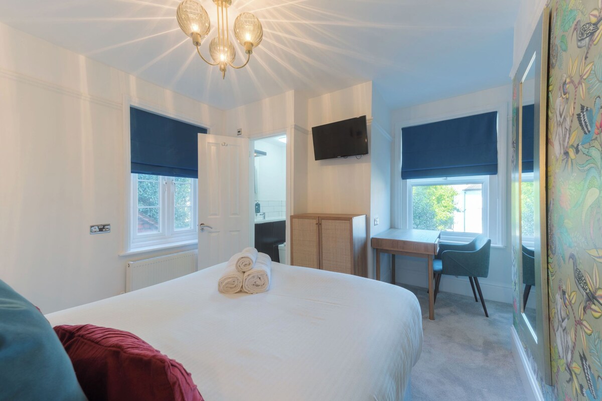 Un dormitorio con una cama grande, un escritorio, una silla, un televisor y una ventana con vistas.