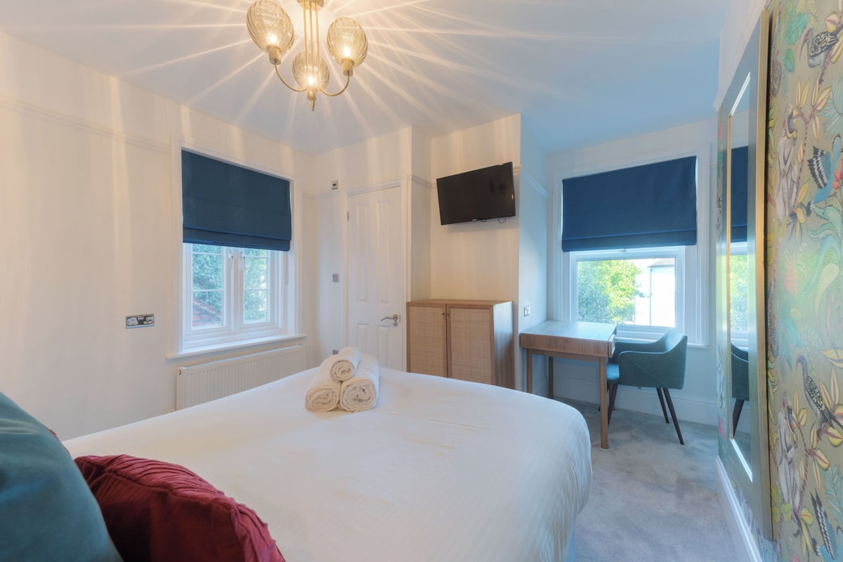 Un dormitorio con cama, escritorio, televisor y ventana con vistas.