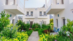 A courtyard with a central pathway surrounded by lush greenery and white buildings with balconies. - Via Farilya Hotel (Bodrum)