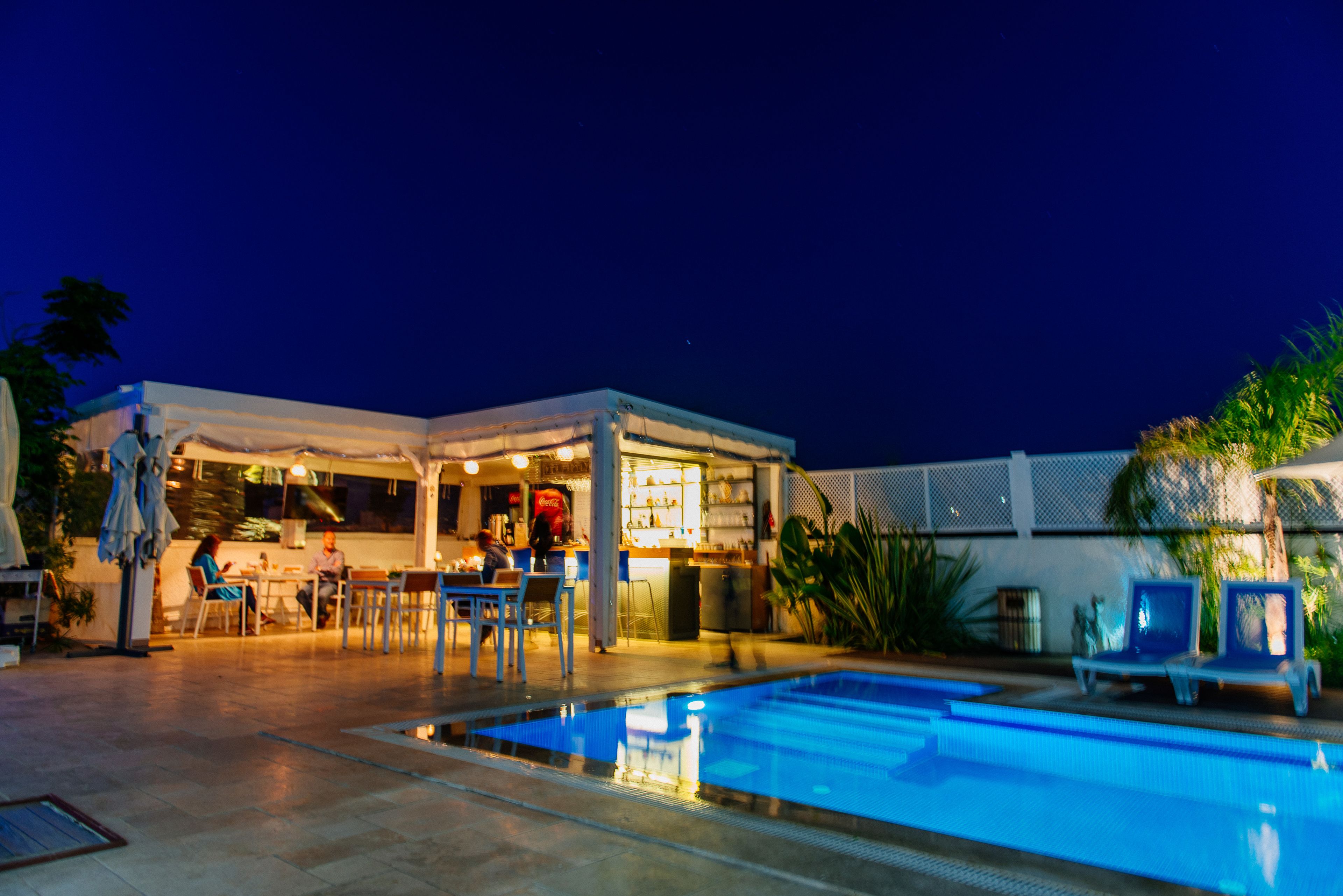 Zona junto a la piscina con un bar y asientos.