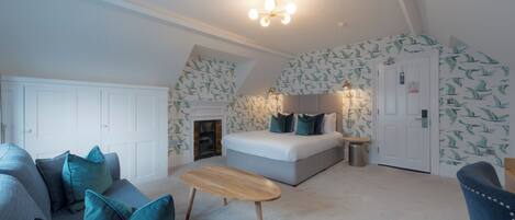 A bedroom with a bed, a sofa, a small table, and a fireplace.