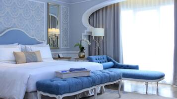 A bedroom with a large bed, a blue sofa, and a small table with a lamp.