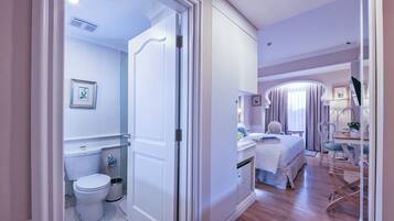 A hotel room with a bathroom, a bed, a desk, and a chair.