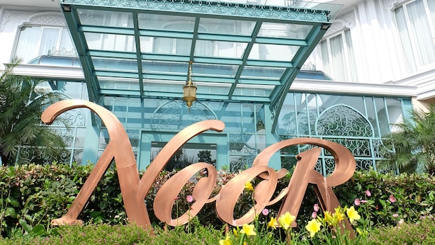 A hotel entrance with a large 'Noor' sign, a glass canopy, and a white building with balconies. - Noor Hotel (Bandung)