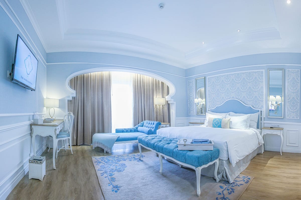 A bedroom with a large bed, a sitting area, and a desk.
