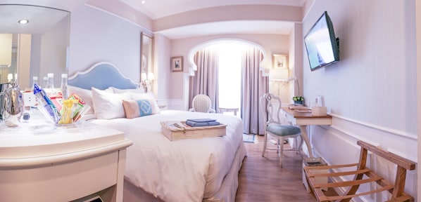 Una habitación de hotel con cama, mesita de noche, silla, escritorio y televisor.