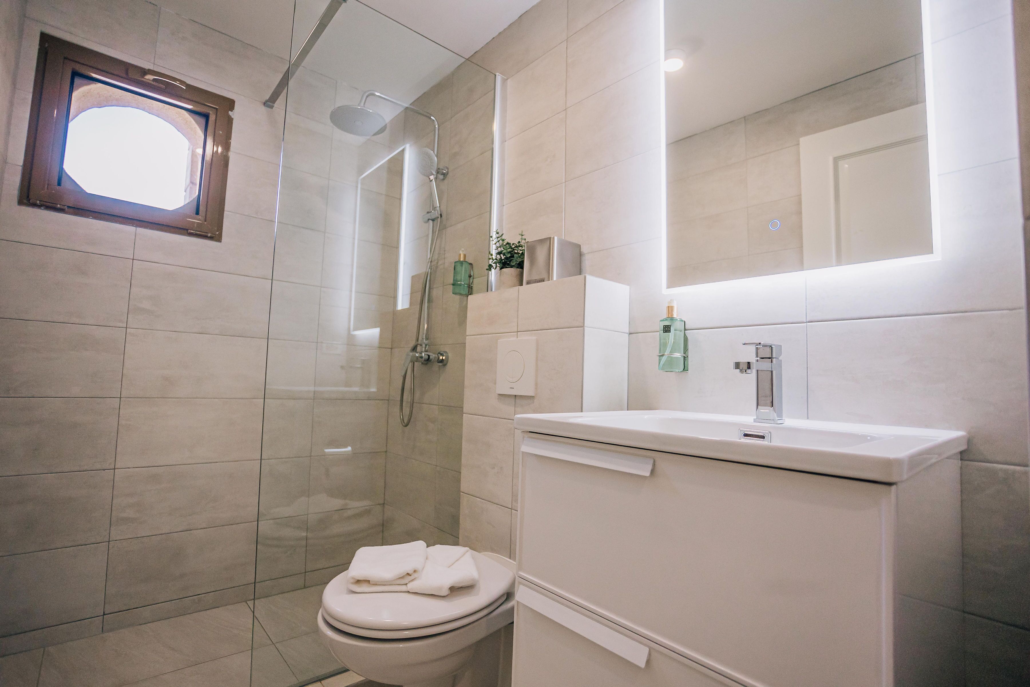 A modern bathroom with a toilet, a shower, and a sink.