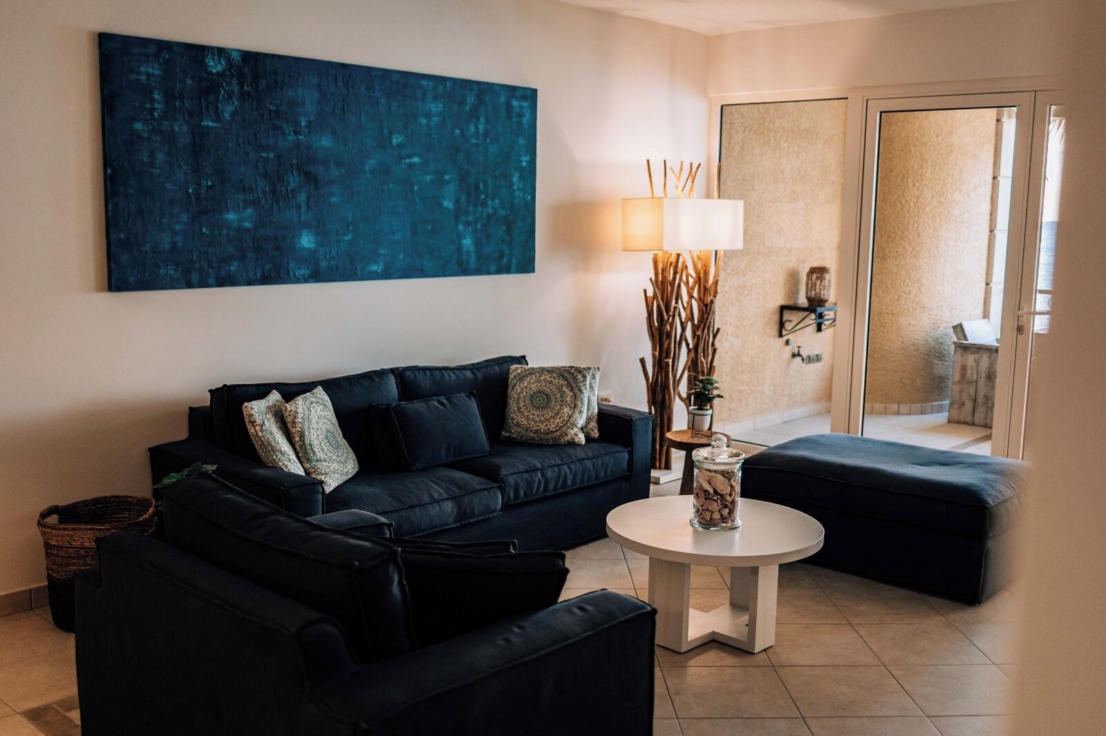 A modern living room with a dark-colored sofa, a round coffee table, and a large abstract painting on the wall.