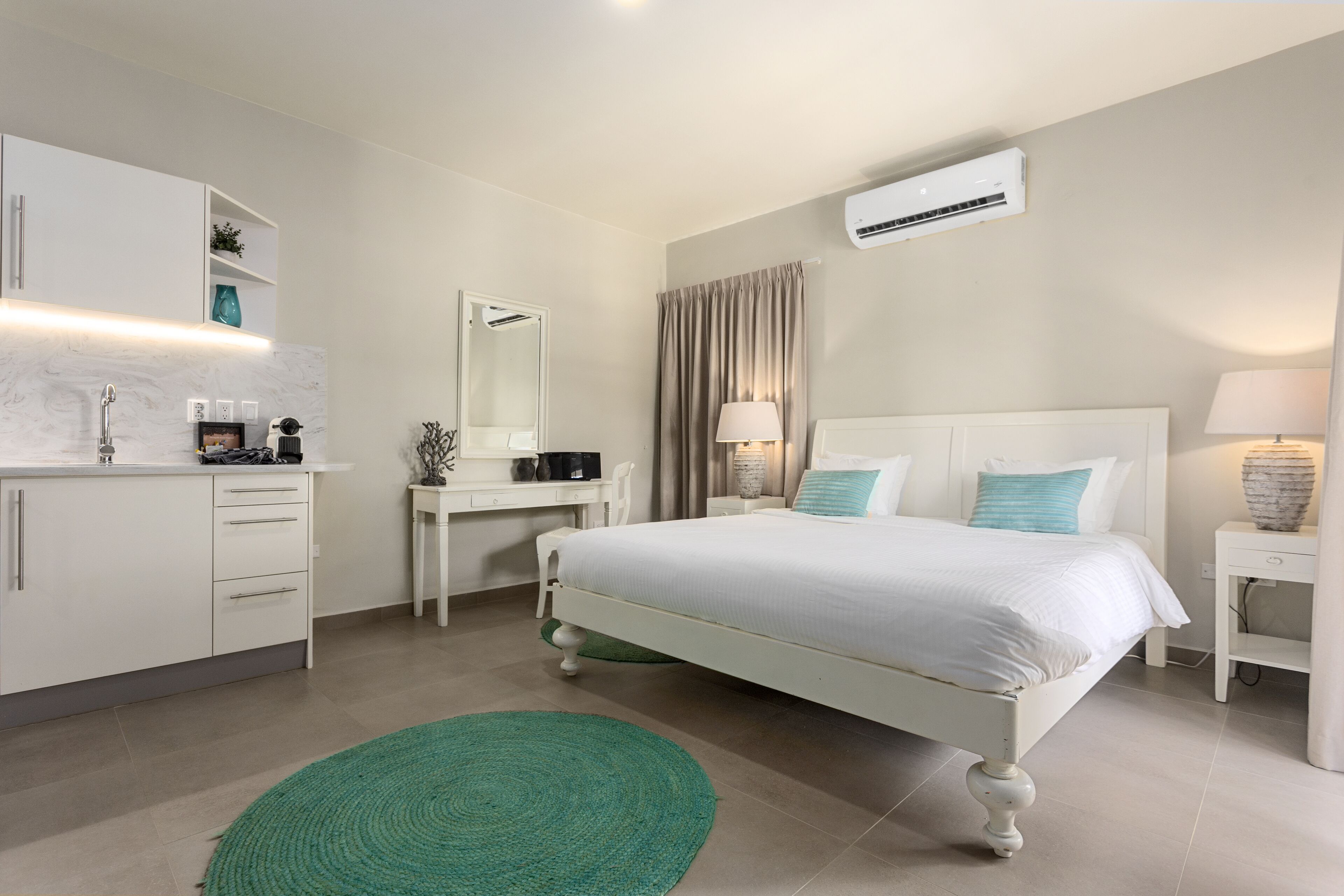 A modern bedroom with a white bed, a desk, and a vanity.