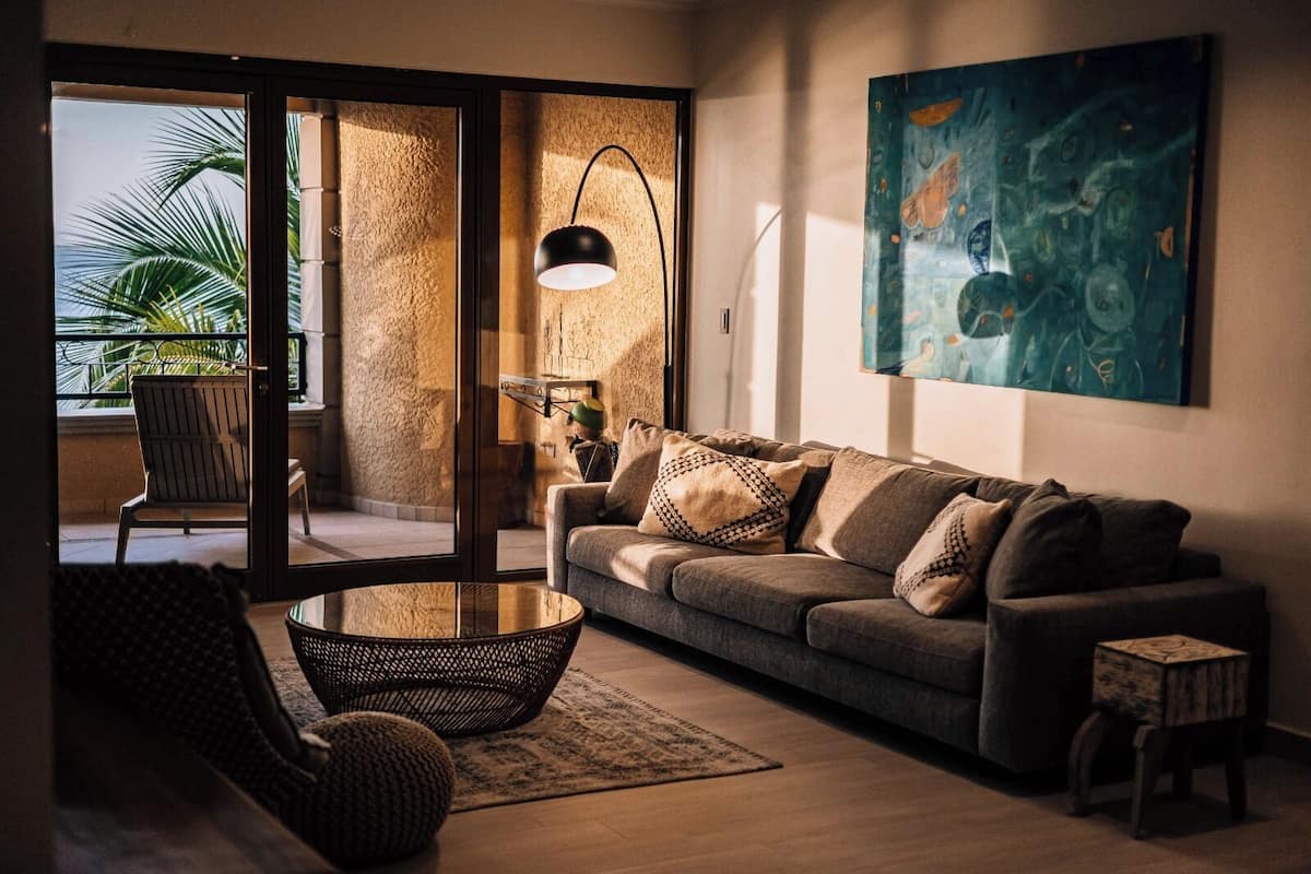 A living room with a sofa, a round coffee table, a chair, a lamp, and a painting on the wall.
