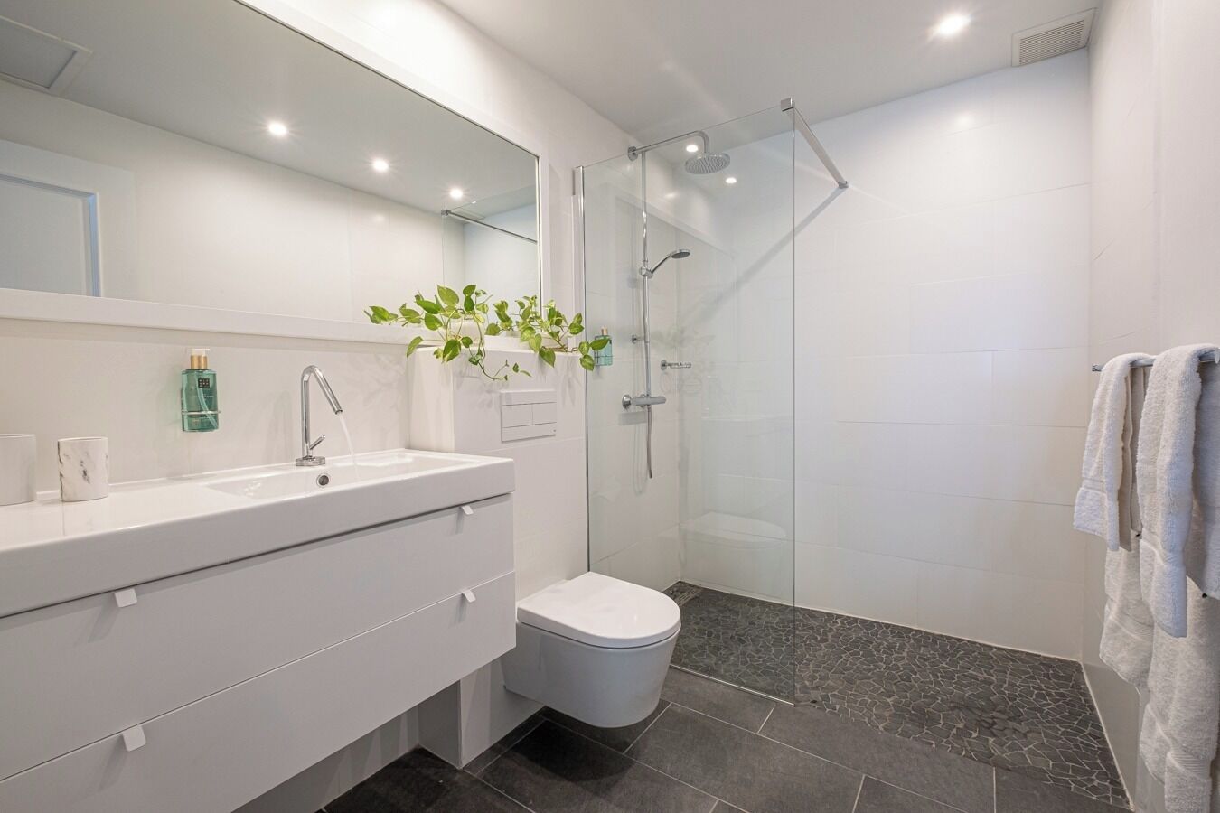 A modern bathroom with a glass-enclosed shower, a white sink, and a toilet.