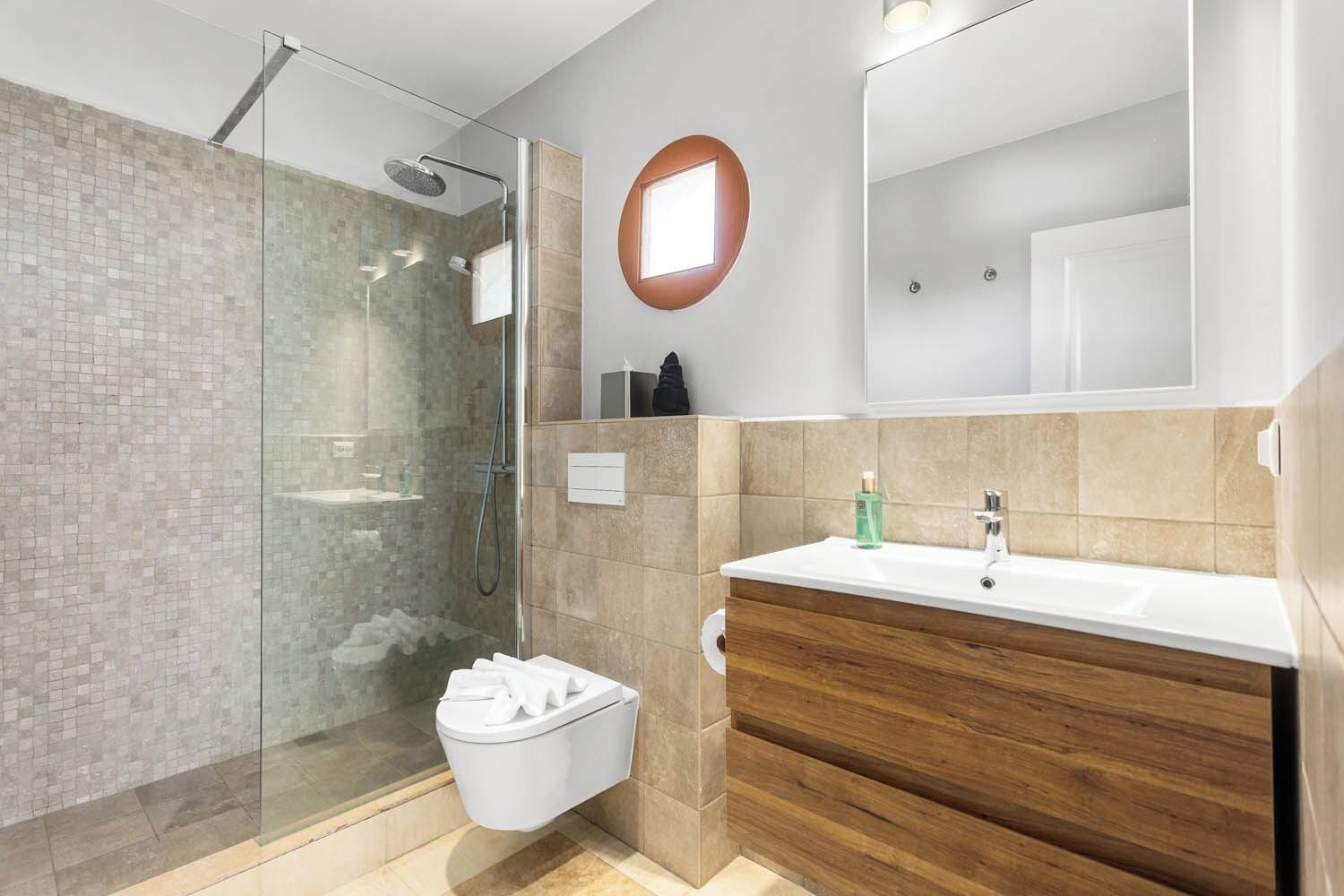 A modern bathroom with a glass-enclosed shower, a wooden vanity, and a large mirror.