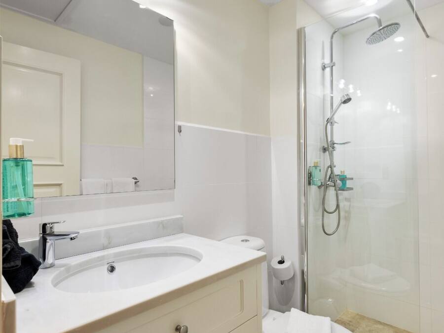 Une salle de bain moderne avec un grand miroir, un meuble-lavabo, un lavabo, des toilettes et une douche à parois de verre.