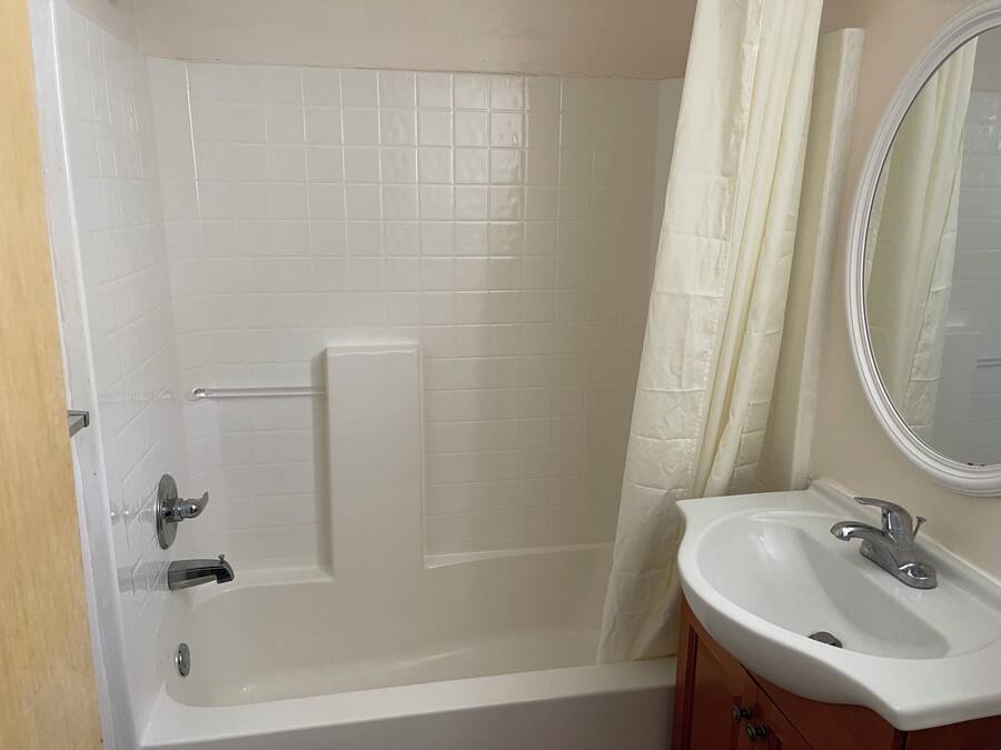 A bathroom with a bathtub, a sink, and a mirror.