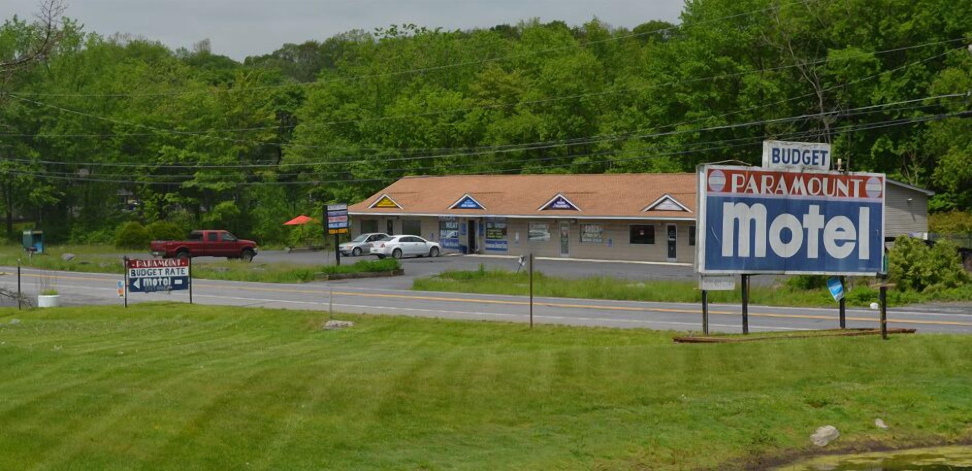 A motel with a signboard, a red truck parked in front, and a building with a signboard in the background.