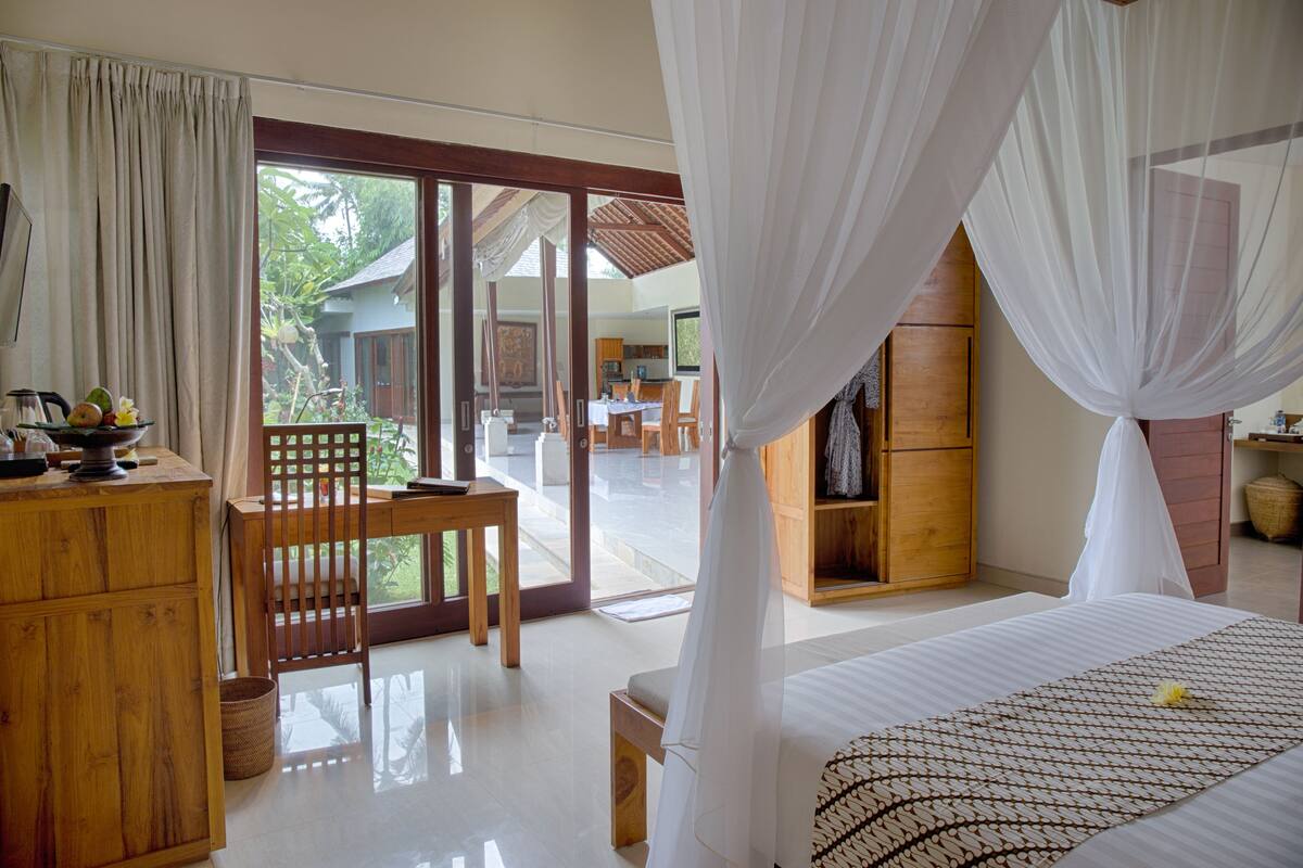 Un dormitorio con cama, un escritorio de madera, una silla y vistas al exterior.