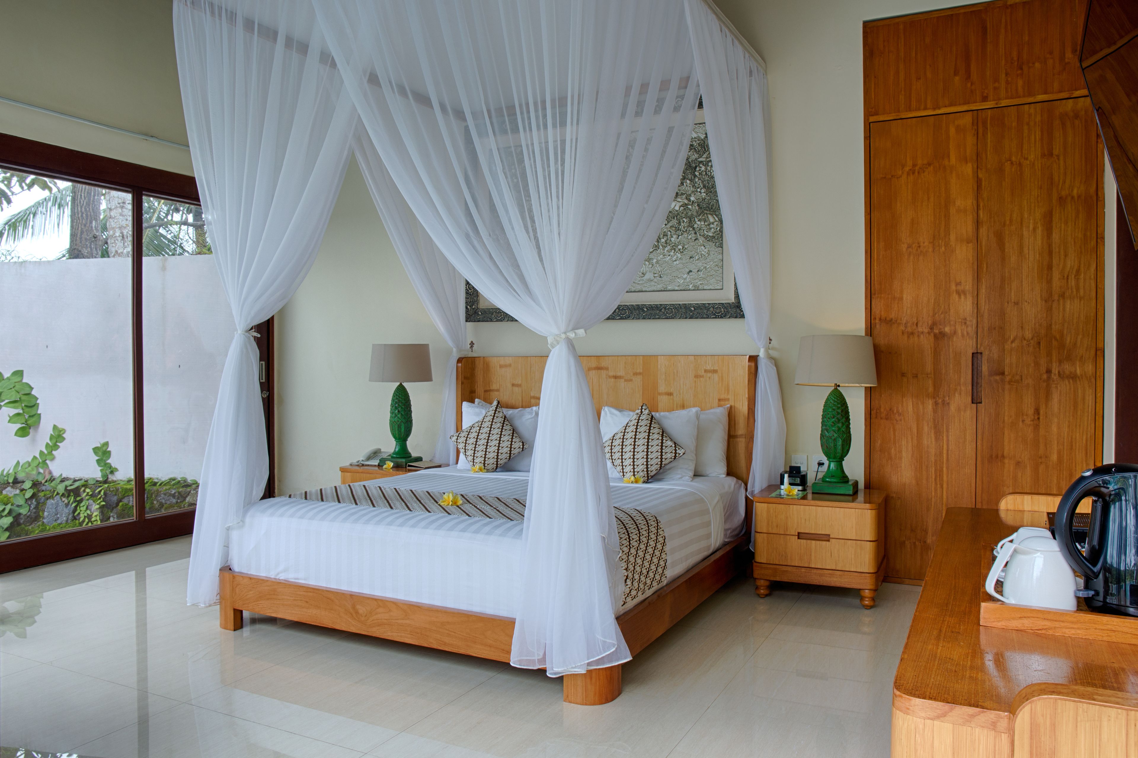 Un dormitorio con cama con dosel, cabecera de madera, mesitas de noche con lámparas y un armario de madera.