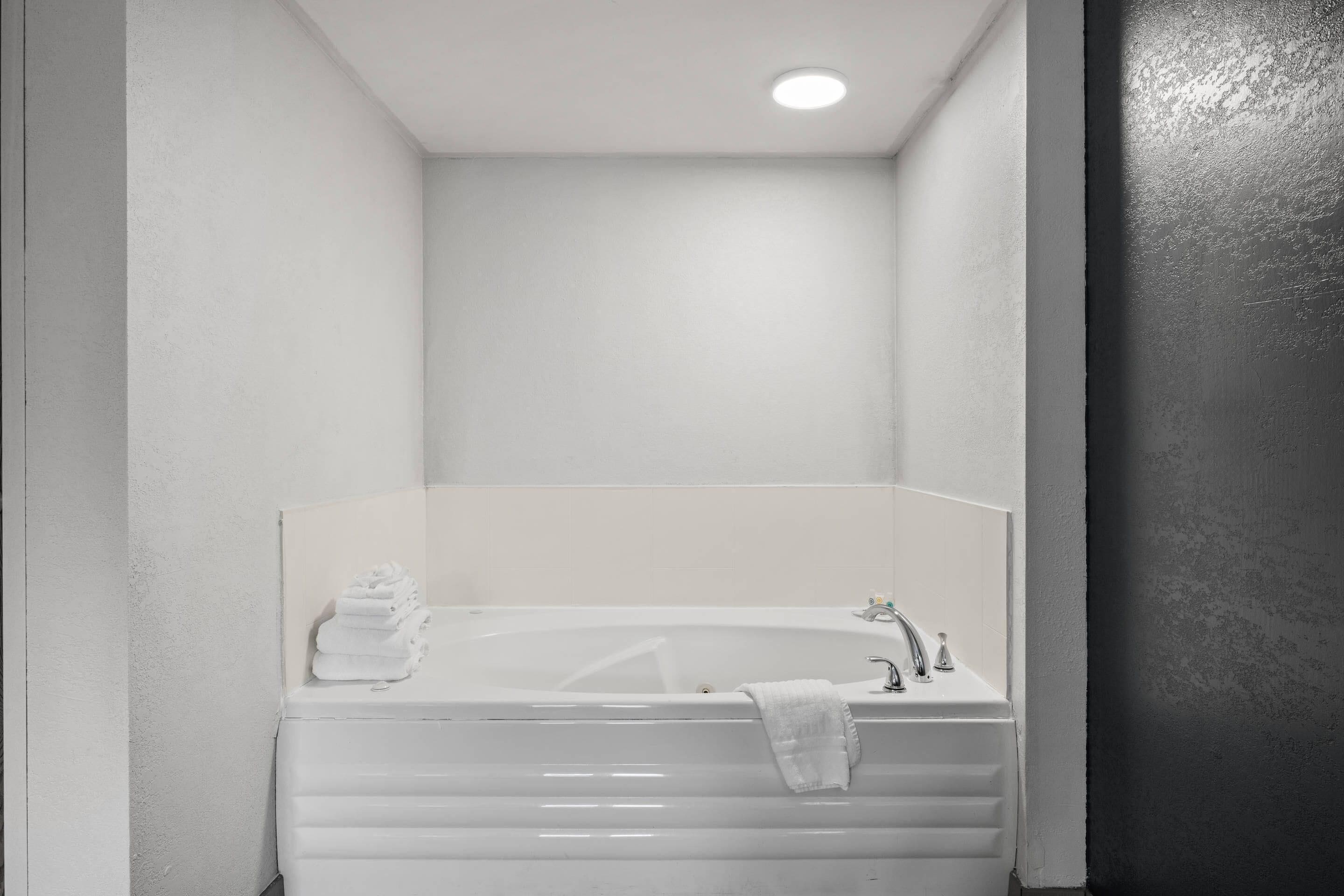 A small, white bathroom with a bathtub, a sink, and a towel rack.